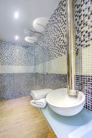 Un baño con paredes de mosaicos, una ducha y un lavabo.