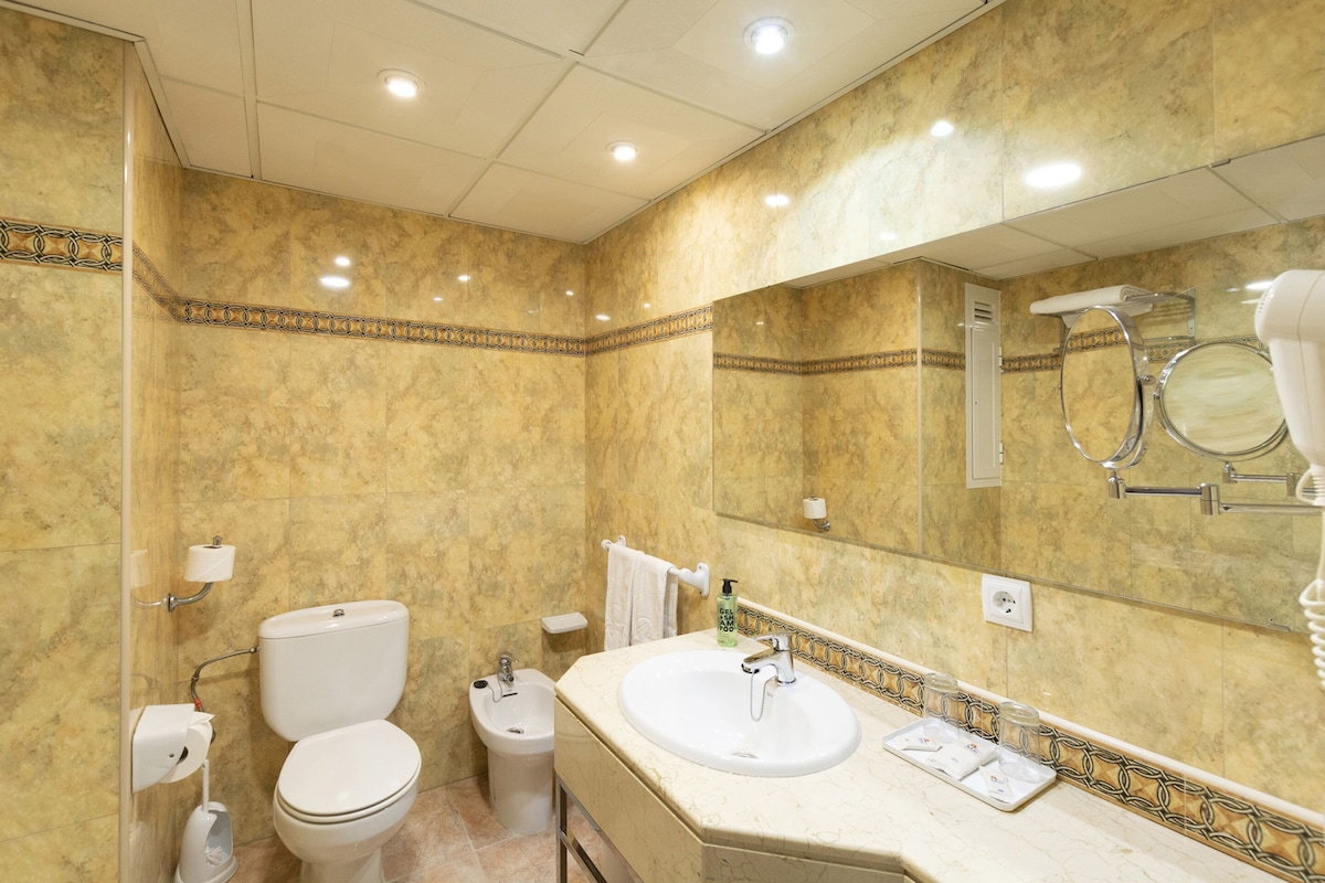 Un baño con inodoro, bidé, lavabo y espejo.