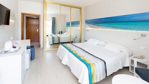 Een hotelkamer met een groot bed, een bureau, een stoel, een spiegel en een schilderij van een strand.