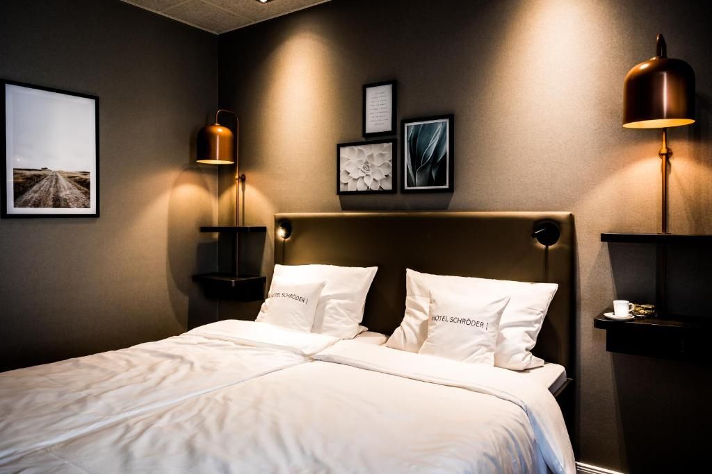 A hotel room with a large bed, two bedside tables, a headboard, and wall-mounted lamps.