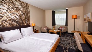 A hotel room with a large bed, a desk, a chair, a small table, and a TV. - Schröder Hotel and Restaurant (Gross Meckelsen)