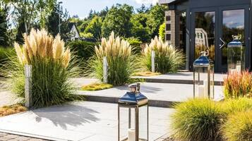 A modern building with a glass entrance, outdoor lanterns, and ornamental grasses.