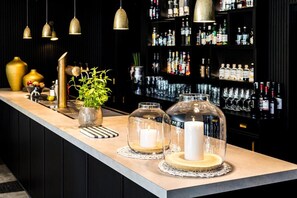 A bar area with a long counter, decorative glass jars, a potted plant, and a shelf of liquor bottles. - Schröder Hotel and Restaurant (Gross Meckelsen)