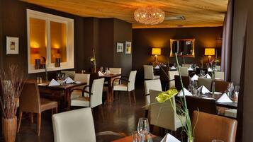 Un restaurante con techo de madera, varias mesas para comer, sillas y lámparas.