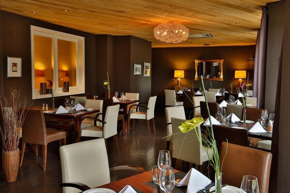 A restaurant with wooden ceiling, multiple dining tables, chairs, and lamps.