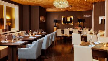 Ein Restaurant mit mehreren Speisetischen, jeweils mit Stühlen und Weingläsern bestückt.