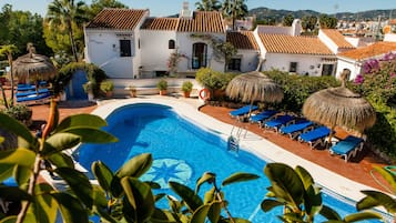 Een buitenzwembad, parasols bij het zwembad en ligstoelen