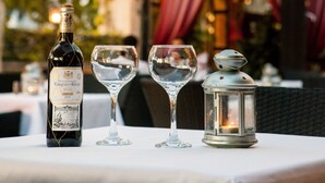 Een tafel met een fles wijn, twee wijnglazen en een lantaarn.