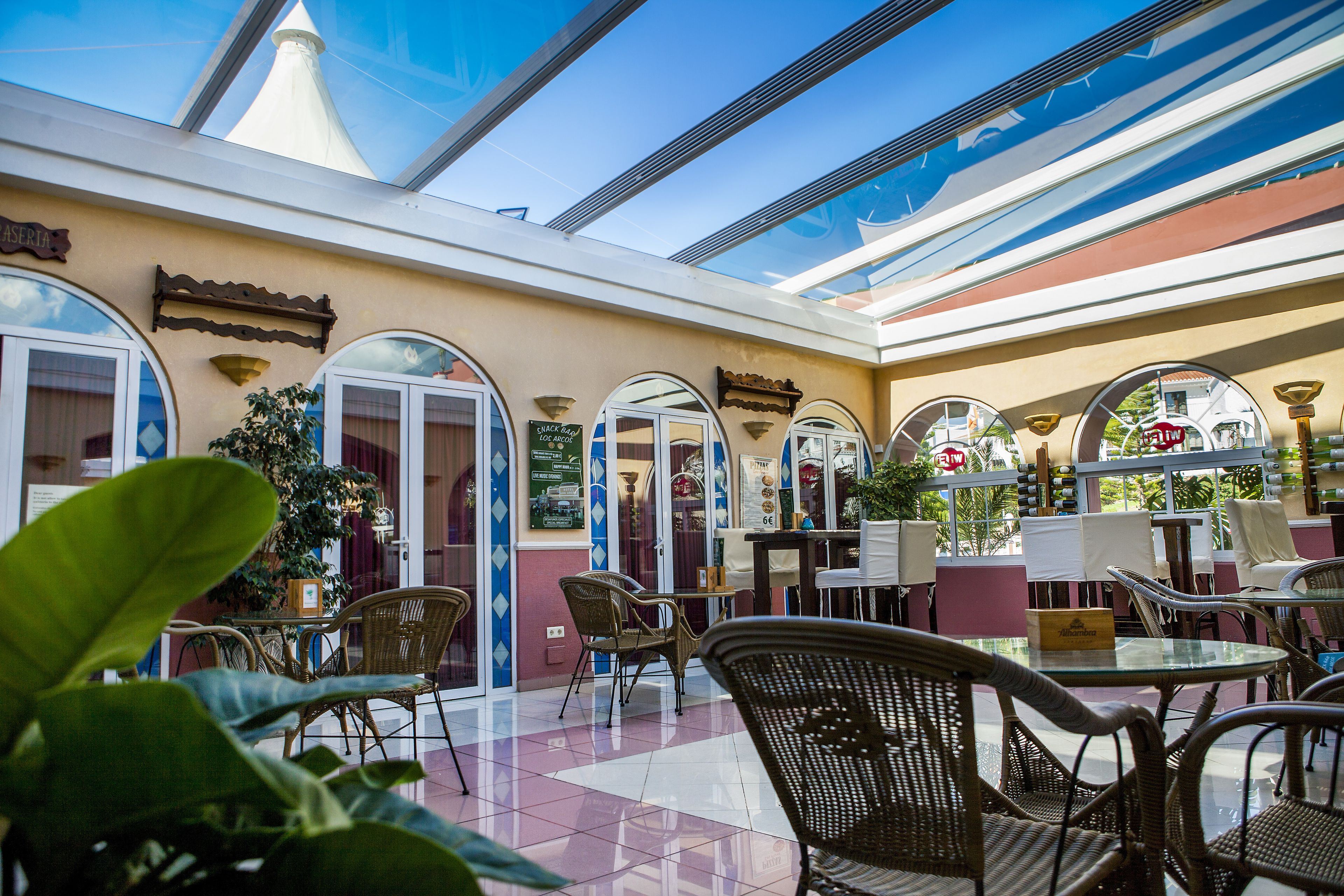 A restaurant with outdoor seating, large windows, and a glass ceiling.