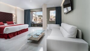 Een moderne hotelkamer met een bed, een bank, een glazen salontafel en een aan de muur bevestigde televisie.