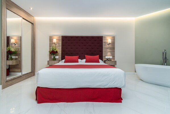 Een moderne slaapkamer met een groot bed, een vastgezet hoofdbord, bedlampen en een badkuip.