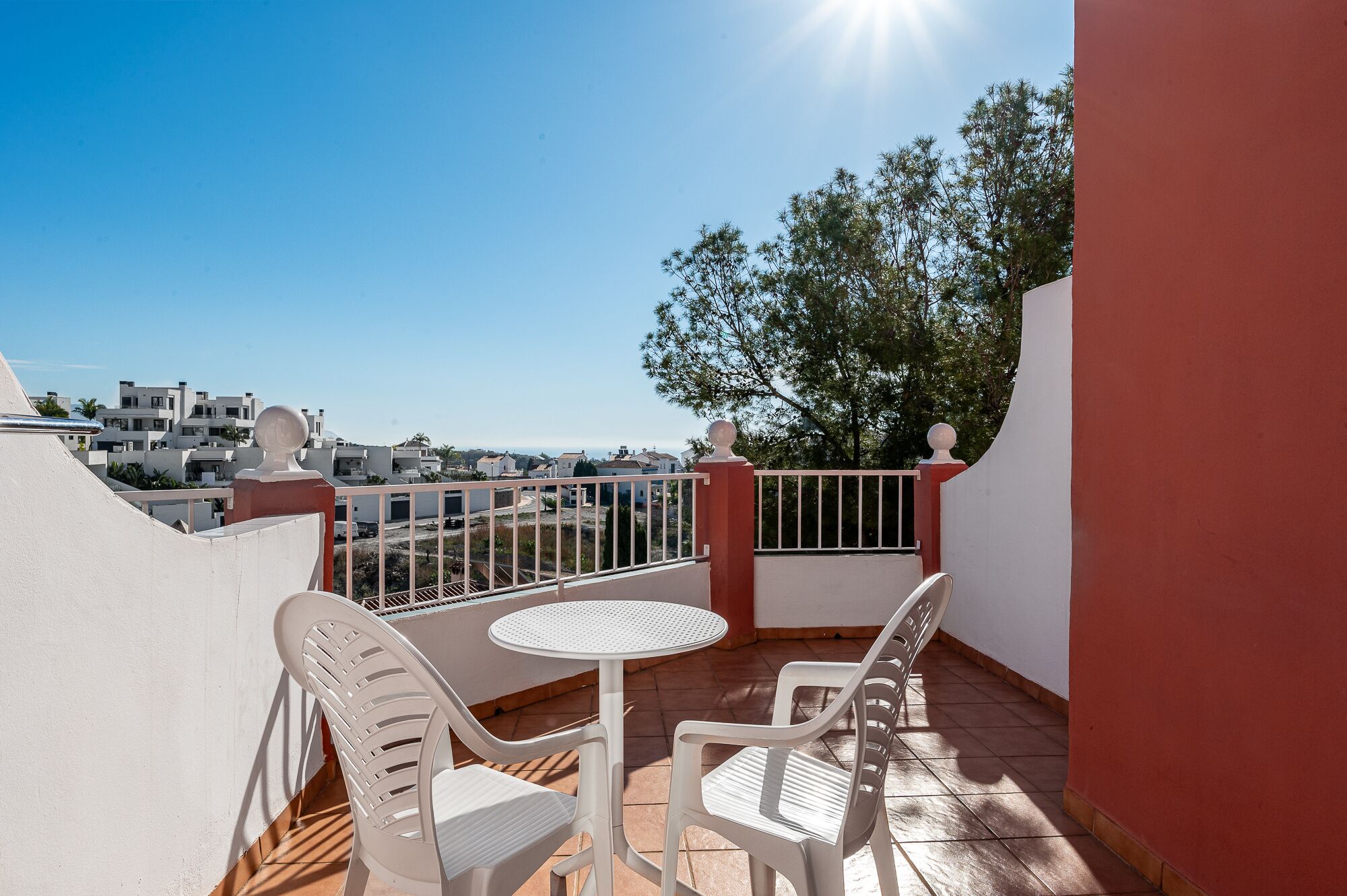 Uma varanda com mesa e cadeiras, vista para edifícios e céu aberto.