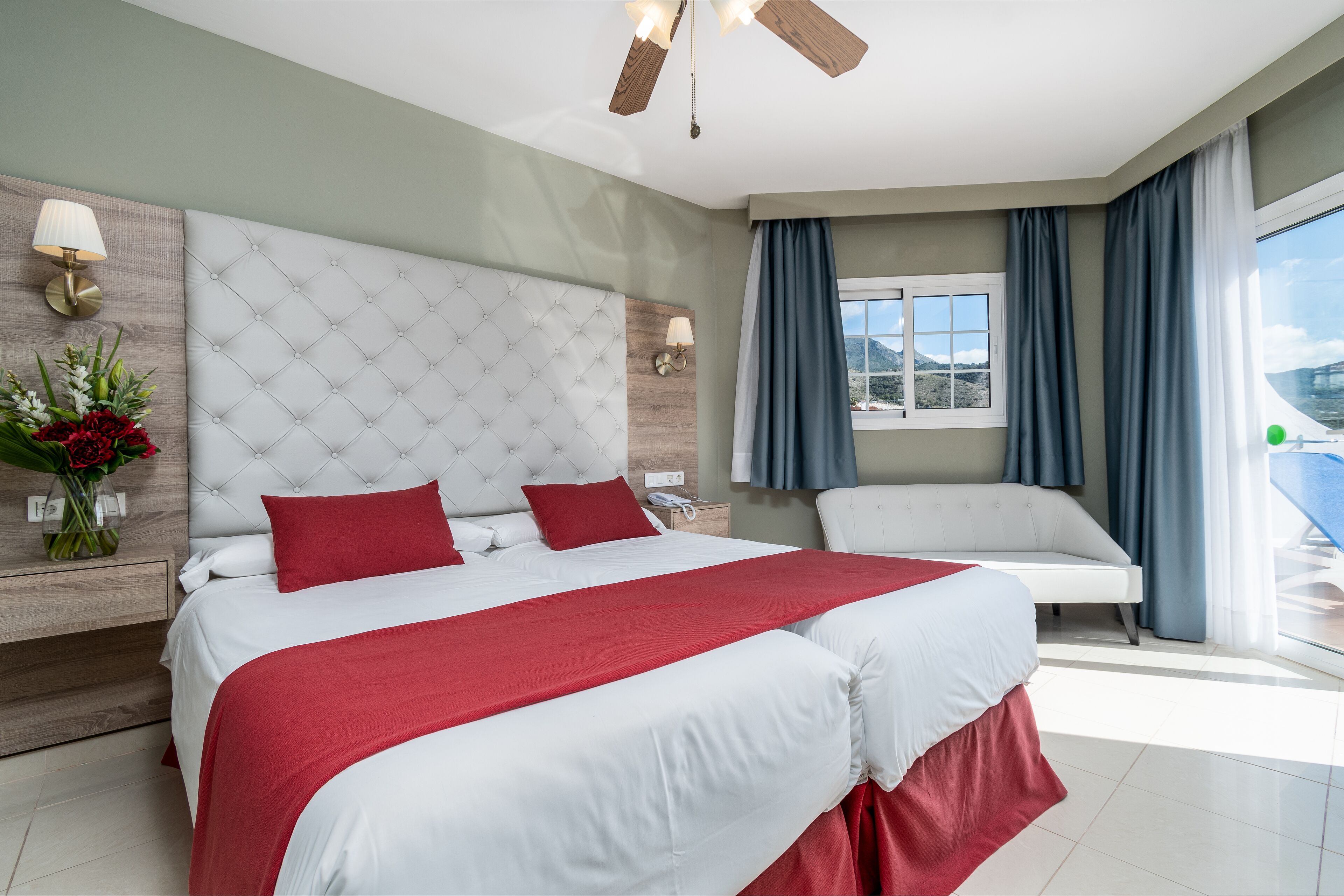 Une chambre d’hôtel moderne, dotée d’un grand lit, d’un canapé, d’une fenêtre avec des rideaux et offrant une vue sur l’extérieur.