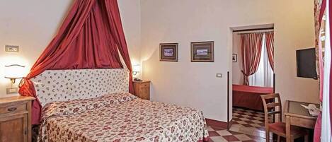 A bedroom with a bed, a desk, and a chair. There are two framed pictures on the wall.