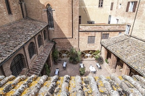 A courtyard with outdoor seating, brick buildings, and a tiled roof. - Il Chiostro del Carmine (Siena)