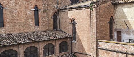 A courtyard with a bell tower, brick buildings, and outdoor seating.