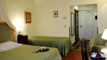 A hotel room with two beds, a small table with candles, a chair, and a door leading to another room.