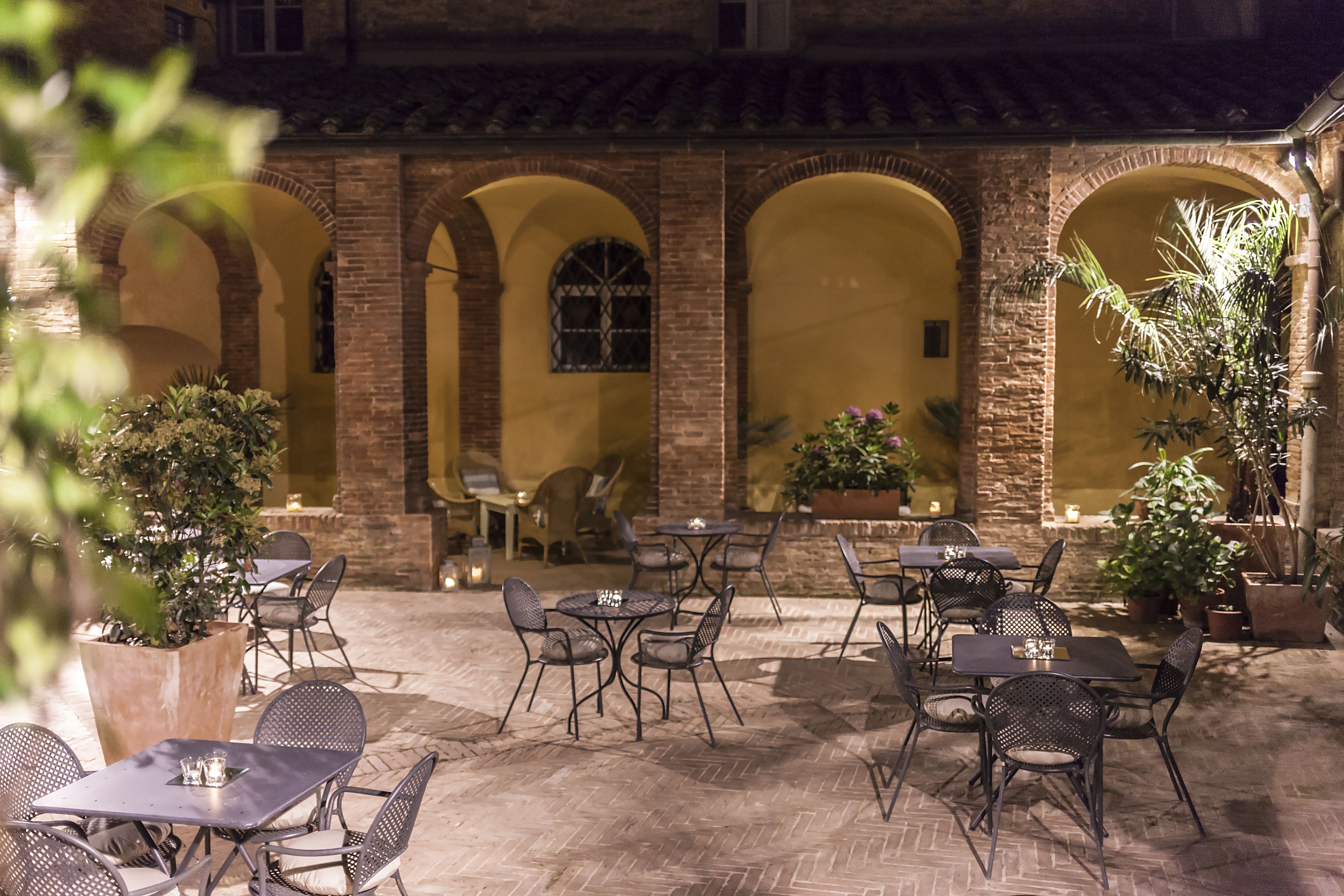 An outdoor patio area with brick arches, tables, and chairs.