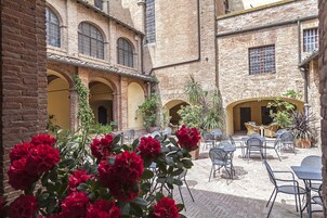 Un cortile con edifici in mattoni, posti a sedere all'aperto e piante in vaso.
