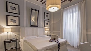 Habitación de hotel ordenada con una cama grande, lámparas de noche, un espejo y cuadros en la pared.