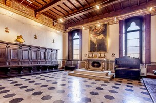 Interno di una chiesa con panche di legno, un altare in legno e un grande dipinto appeso al muro.