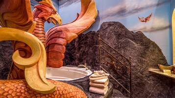 Une composition décorative comprenant un dragon, une baignoire et des serviettes, le tout posé sur une surface rocheuse.