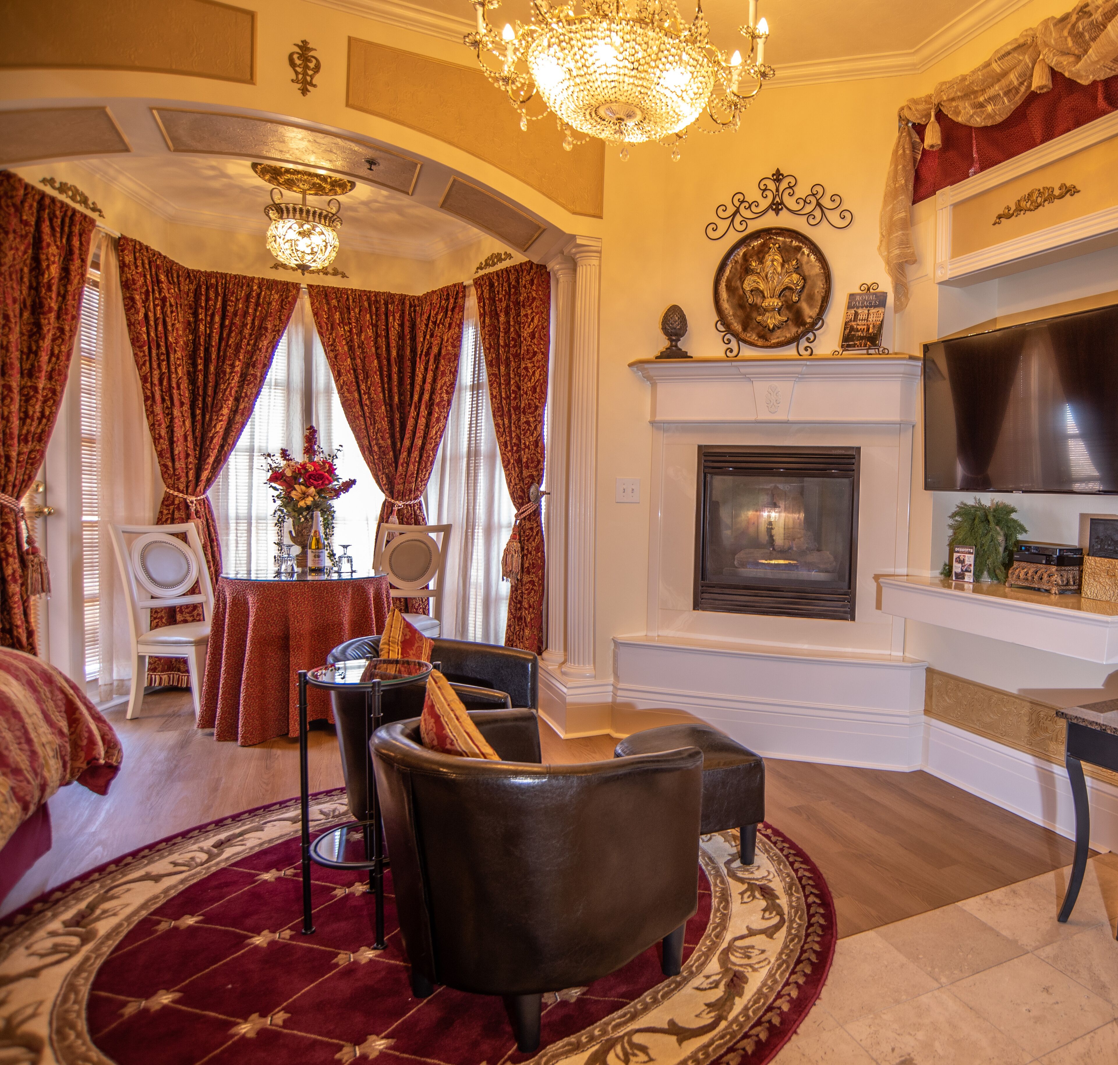 A luxurious living room with a fireplace, elegant furniture, and a chandelier.