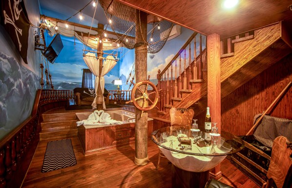 A nautical-themed room with a wooden staircase, a ship's wheel, and a mural of the ocean. - Anniversary Inn - 5th South (Salt Lake City)