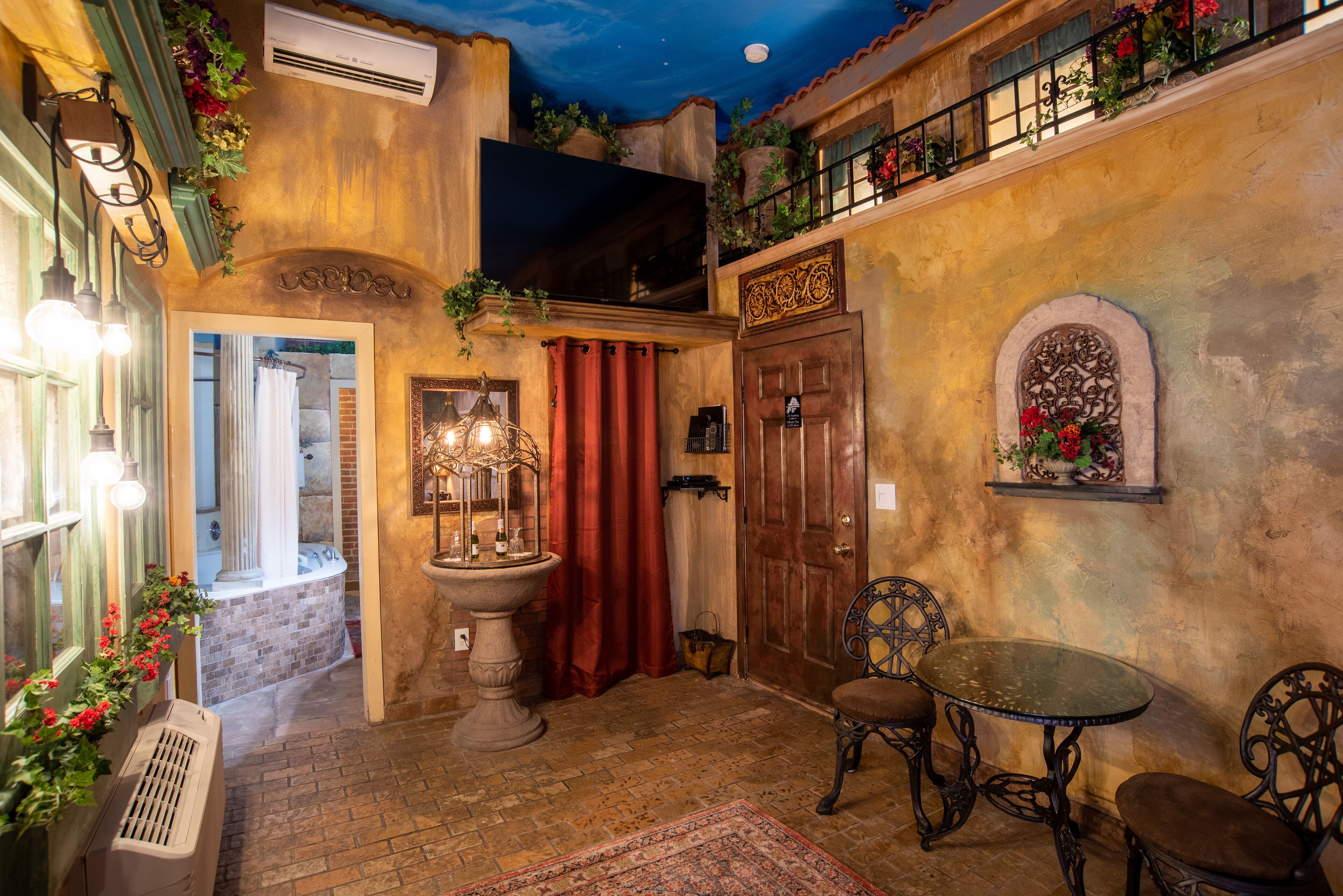 A cozy room with a stone bathtub, a wooden door, and a small table with chairs.