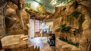 A bathroom with a large bathtub, a shower, and a small table with a chair. - Anniversary Inn - 5th South (Salt Lake City)