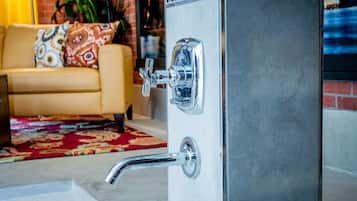 A bathroom with a chrome faucet and a shower control panel.