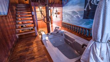 A wooden staircase leading to a room with a large bathtub, nautical-themed decorations, and a mural of the ocean.