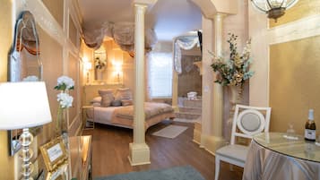 A well-lit bedroom with a bed, bedside table, lamp, and a vase with flowers.