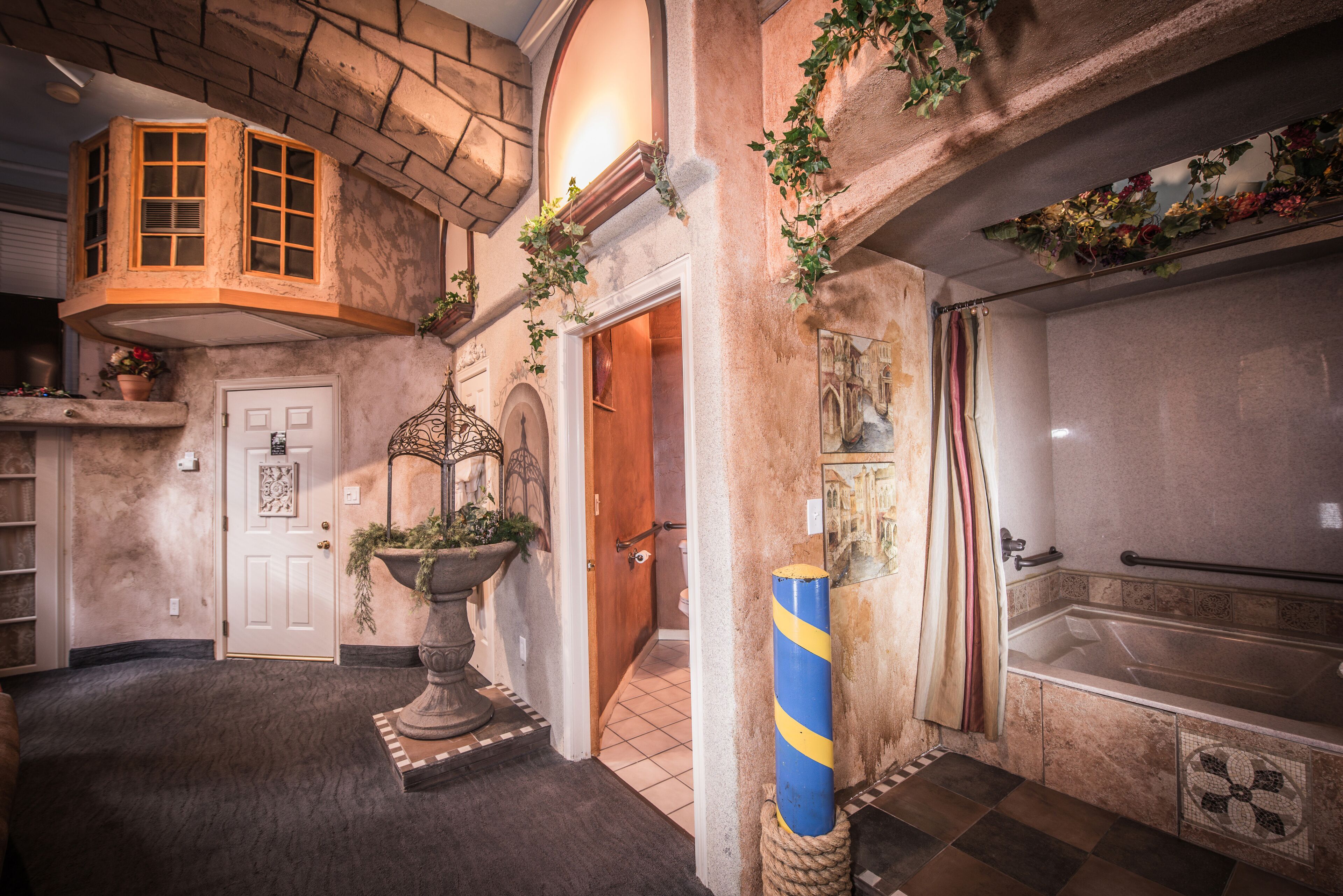 A hotel lobby with a stone facade, a large bathtub, and a potted plant near the entrance.