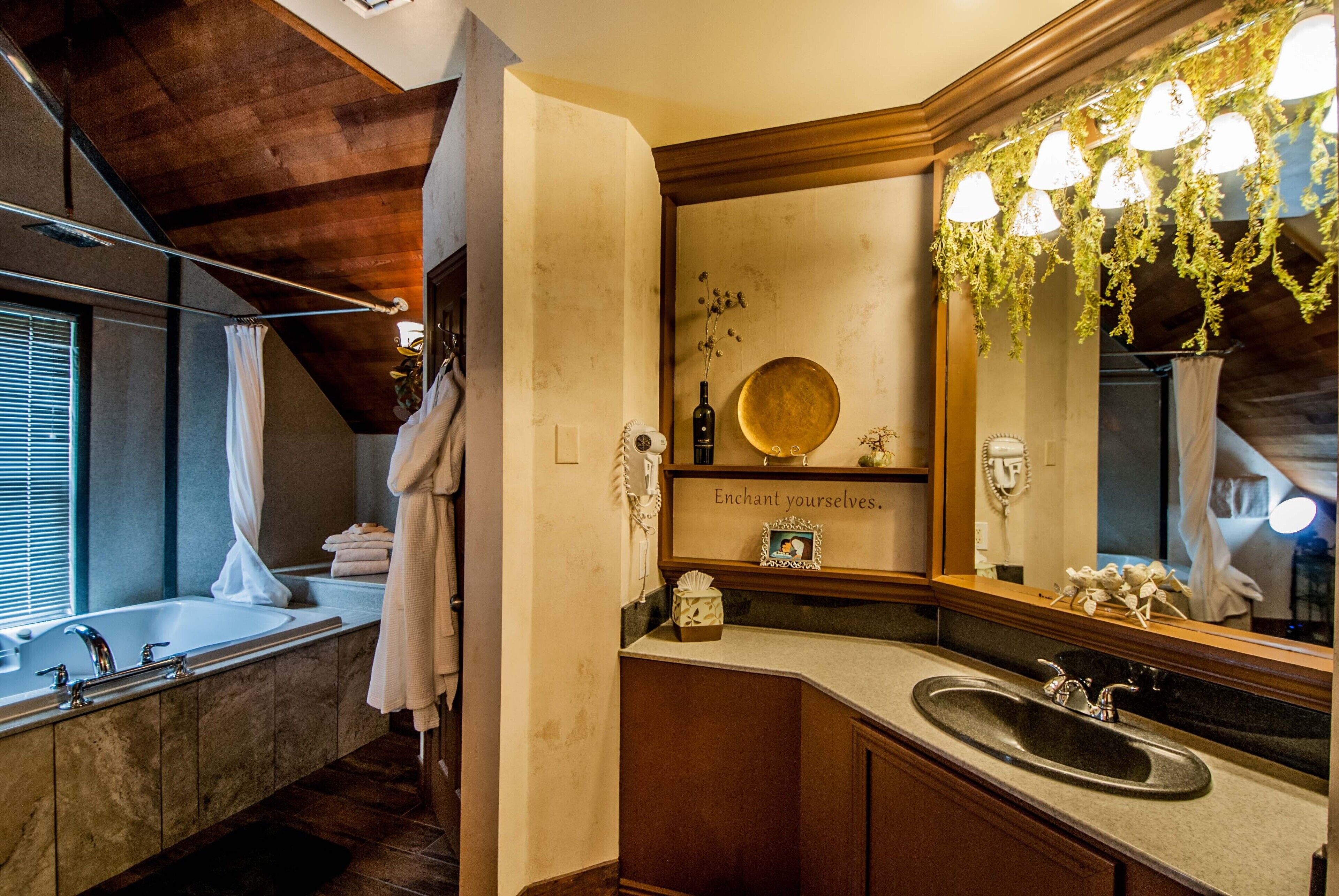 A bathroom with a large bathtub, a vanity with a sink, and a mirror with a decorative light fixture.