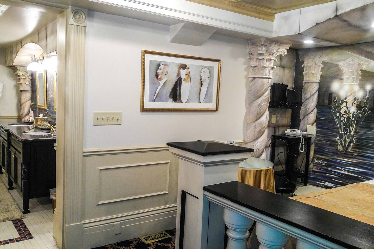 A hotel room with a marble reception desk, a framed artwork on the wall, and a robe hanging on a hook.