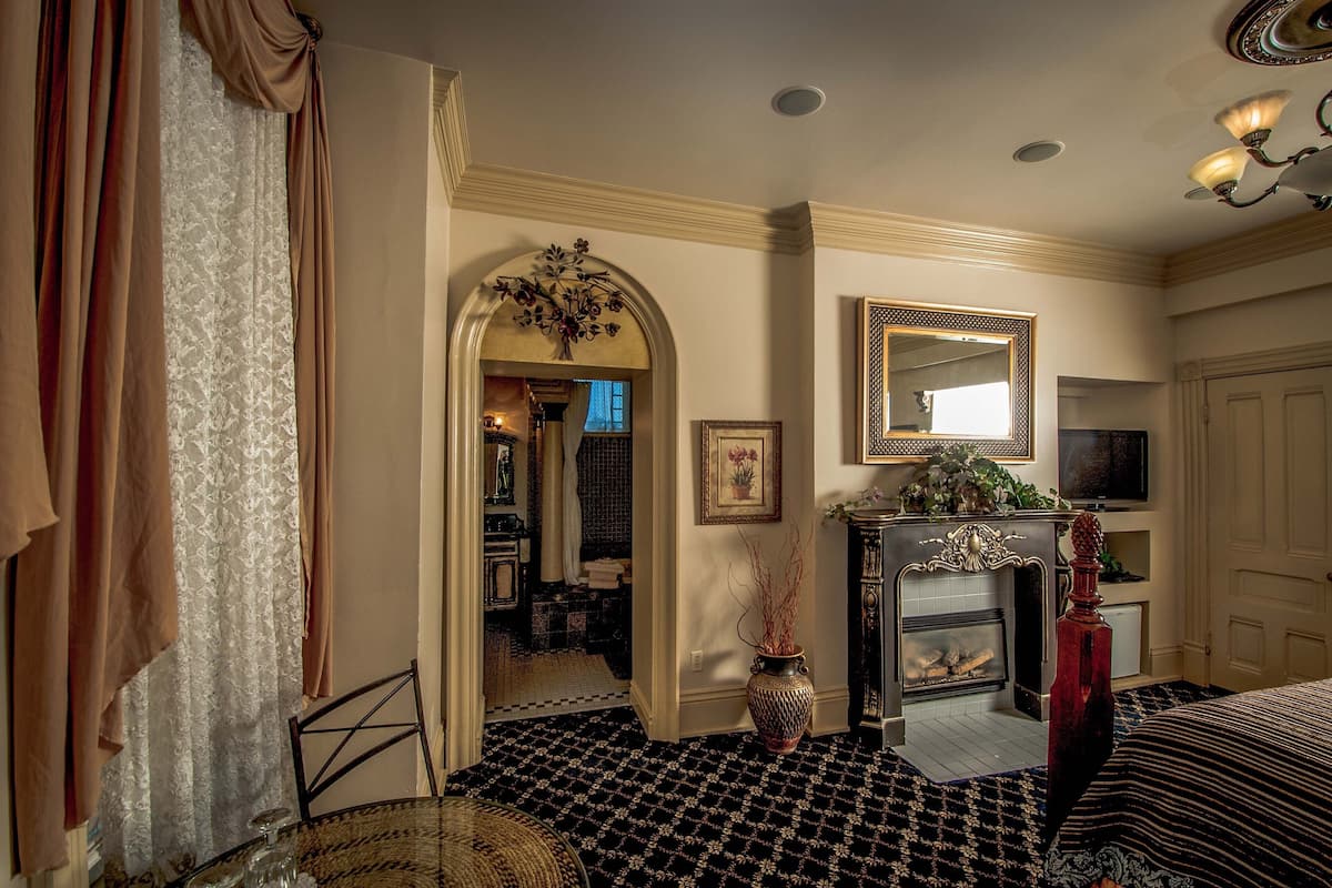 A room with a fireplace, a mirror, and a dining area with a table and chairs.