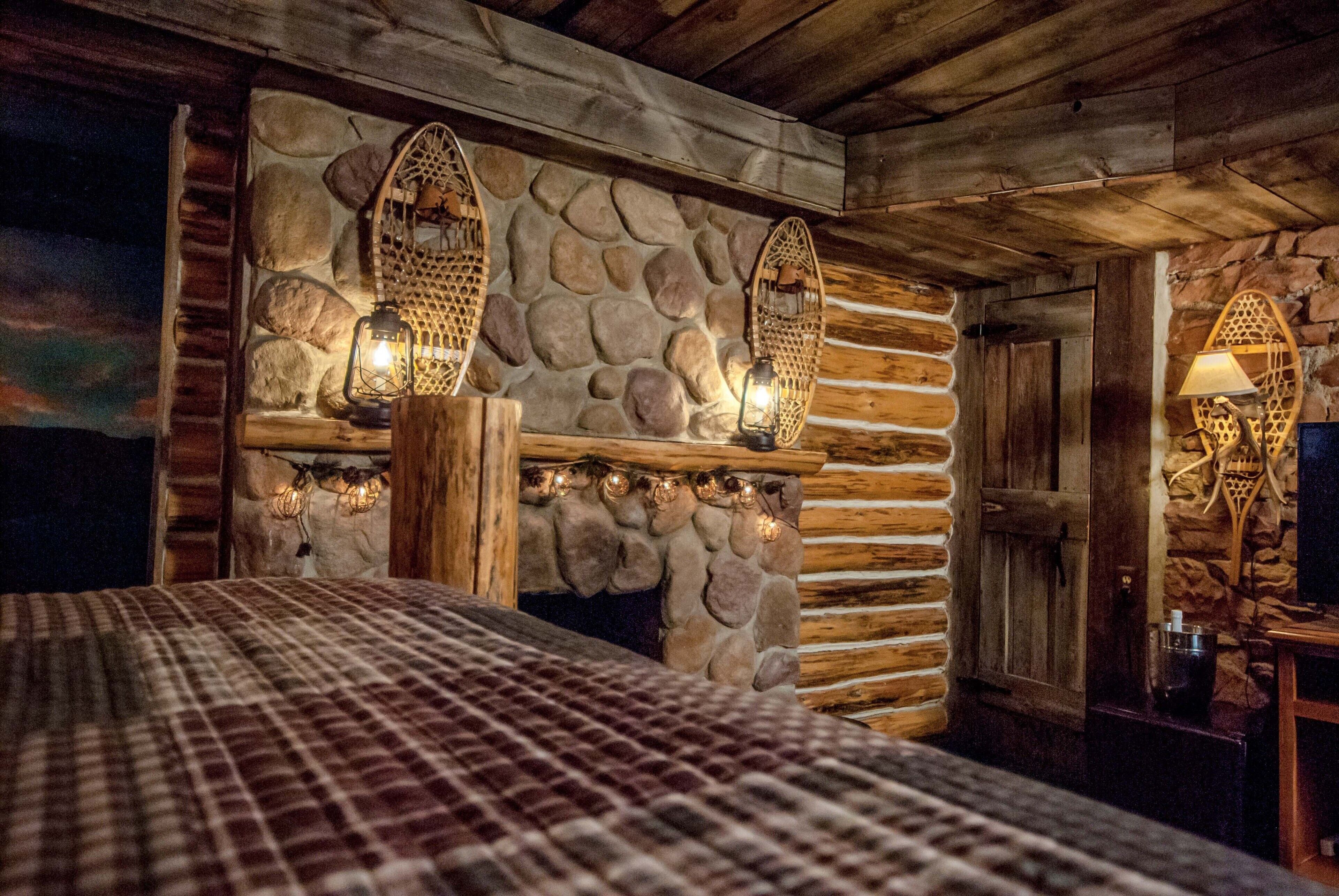 Une pièce rustique avec un mur en pierre, des poutres apparentes et une couvre-lit à carreaux.