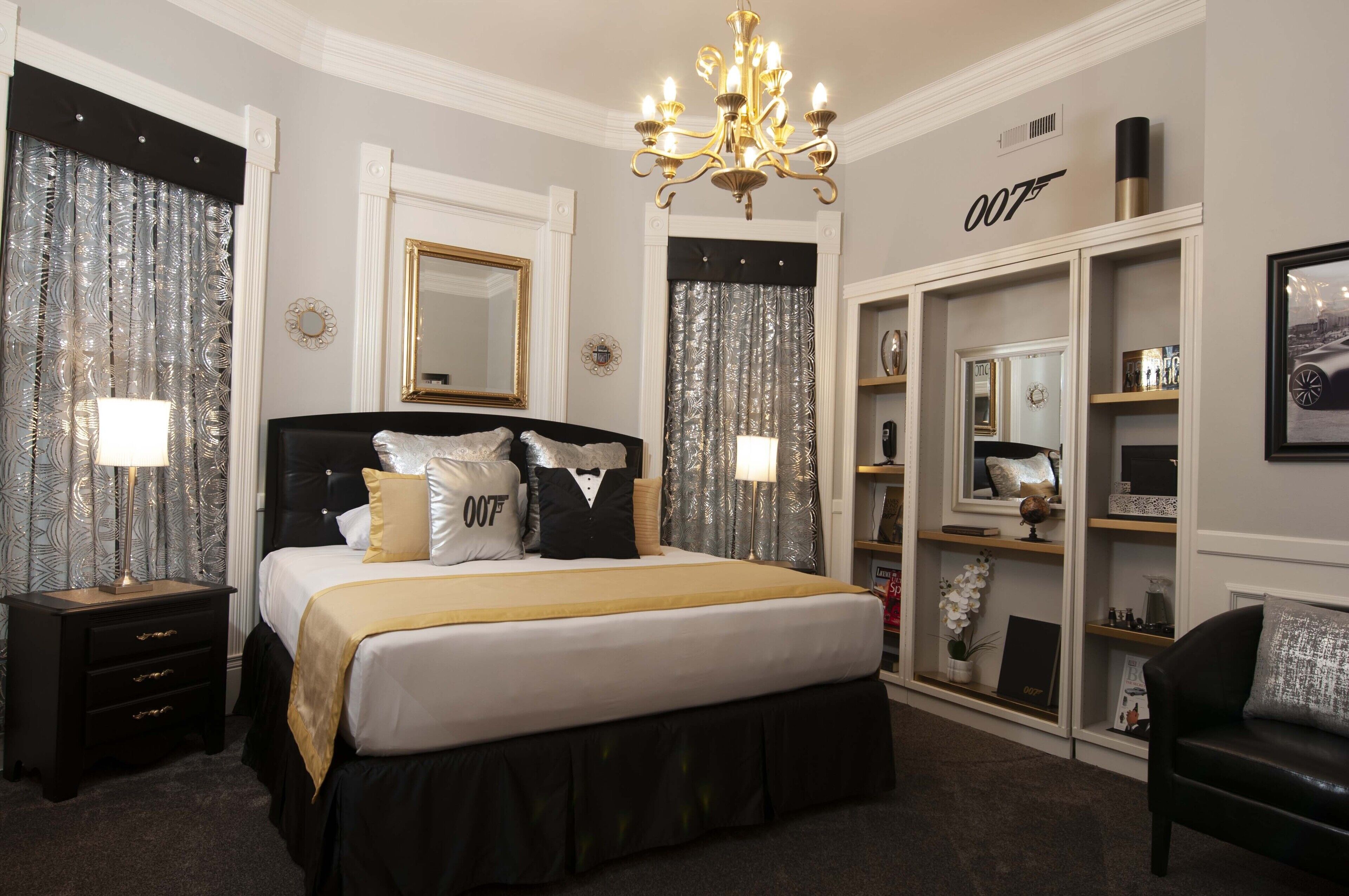 A bedroom with a large bed, a chandelier, a wardrobe, and a mirror.