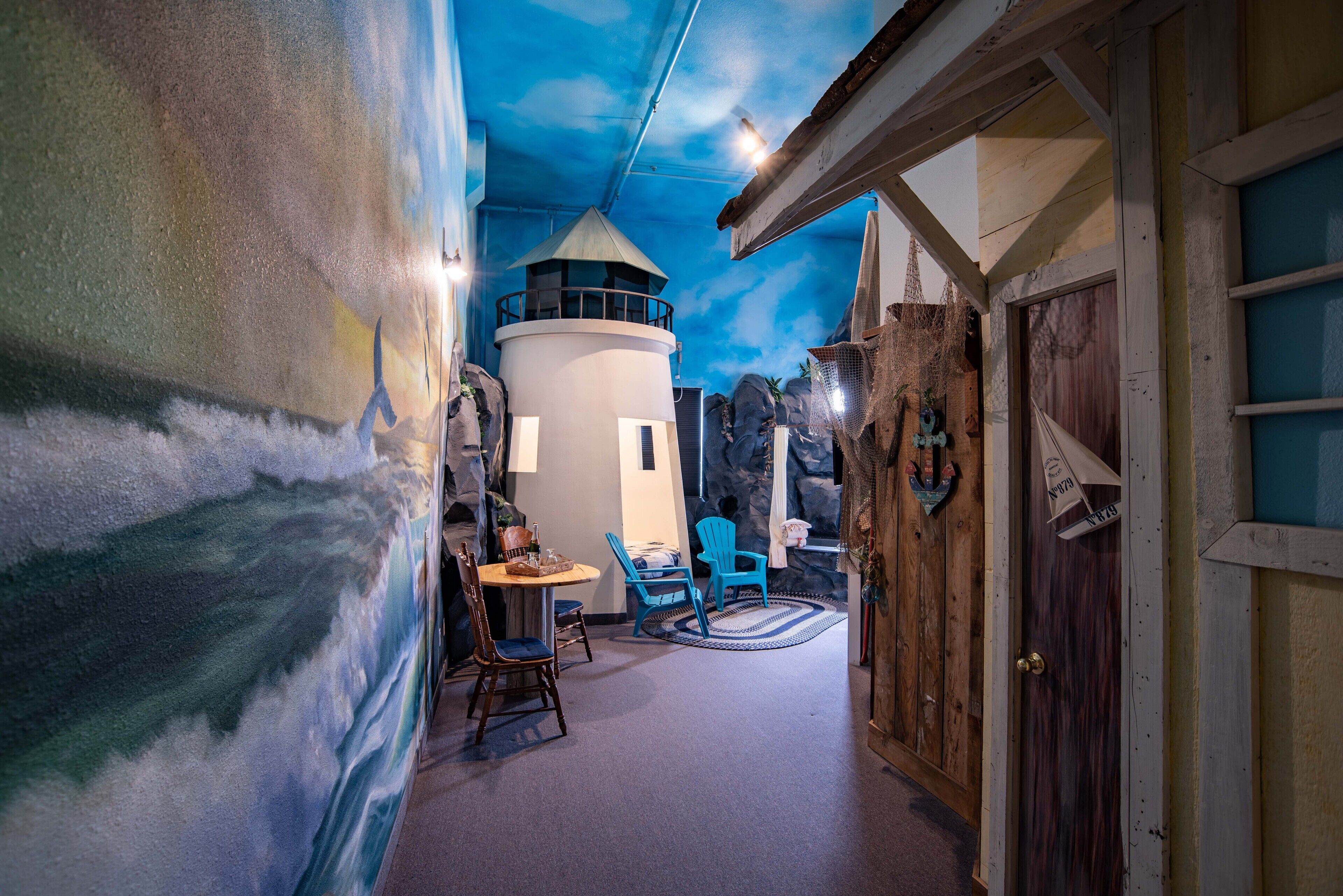 A room with a mural of a lighthouse, a round table with chairs, and a wooden door.