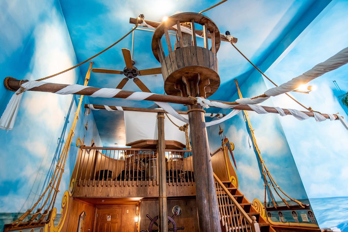 Un décor intérieur sur le thème des navires, avec un pont en bois, un mât central et une échelle de corde.