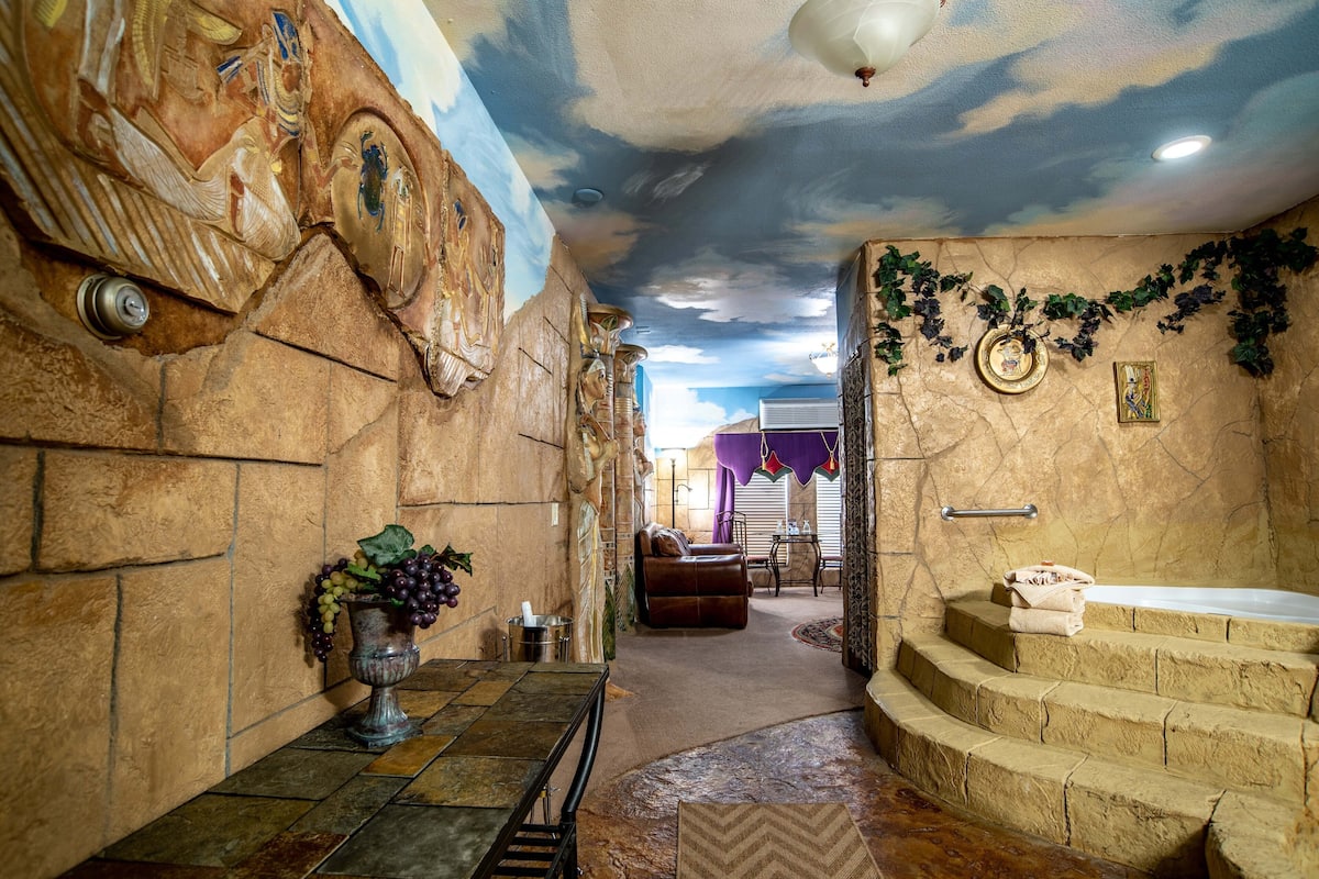 Une salle de bain luxueuse avec un mur en pierre, une baignoire et une fresque au plafond.