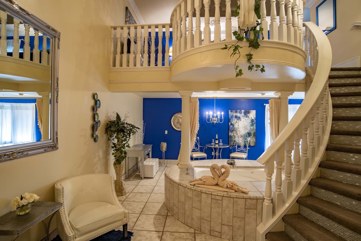 Un intérieur spacieux et élégamment aménagé, avec un grand escalier, une baignoire ronde et un coin salon confortable.