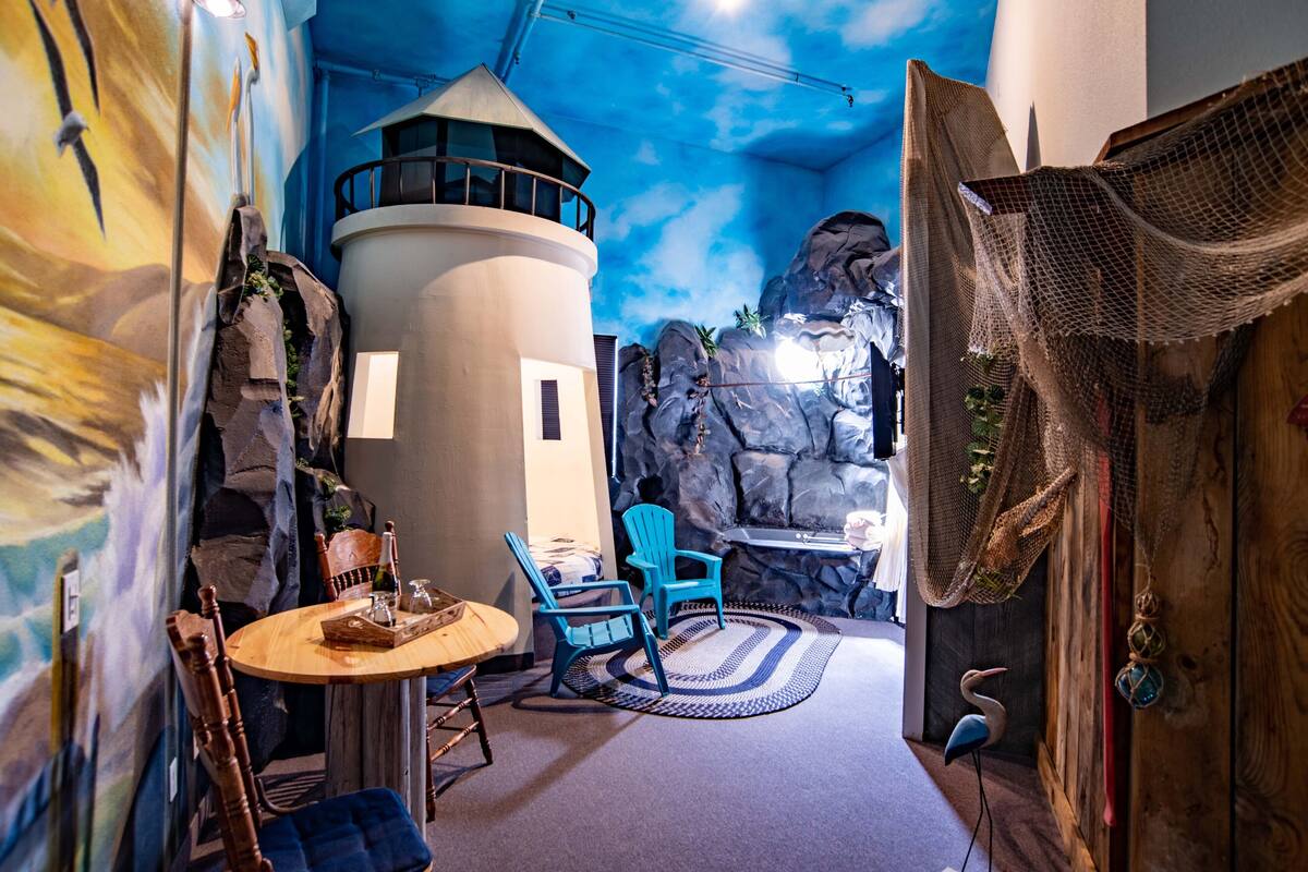 Une pièce avec une table ronde, deux chaises bleues, une chaise en bois, un meuble en bois et une fresque murale.
