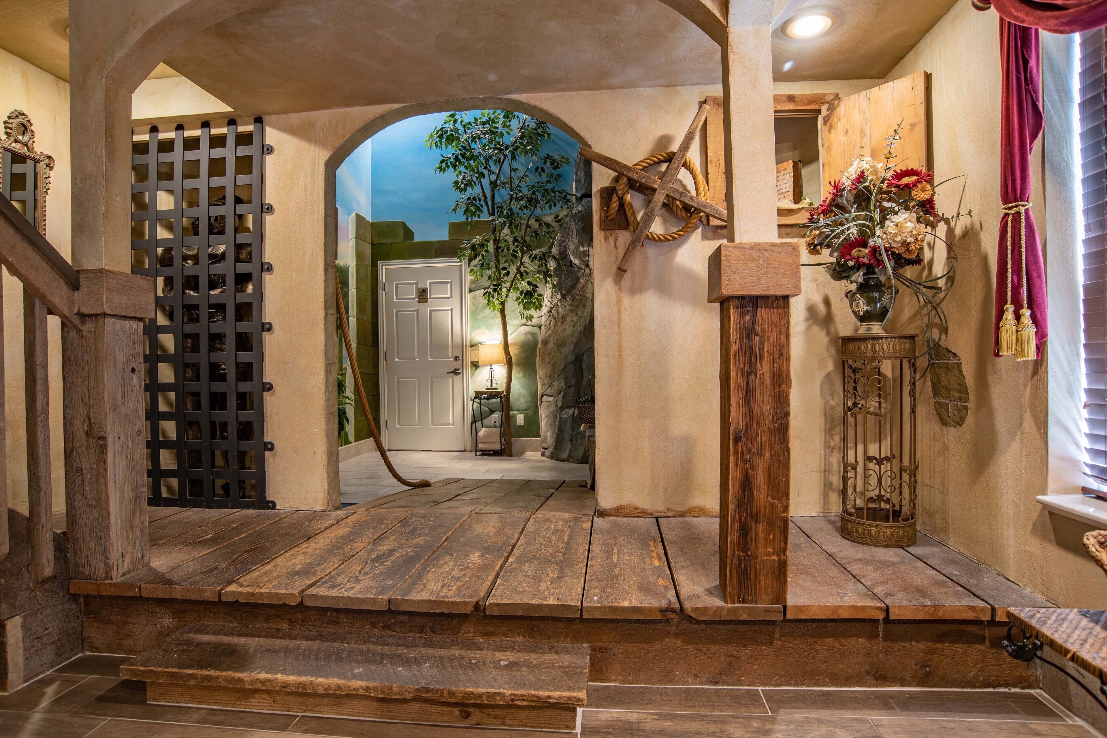 A wooden staircase leading to a room with a door, a plant, and a decorative vase with flowers.