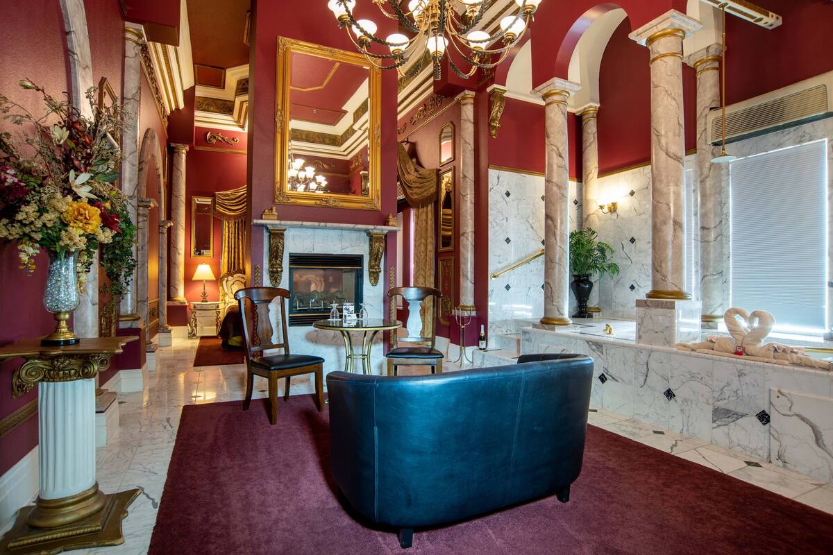 Un hall d’entrée luxueux, avec un sol en marbre, un canapé en cuir bleu, une cheminée et un lustre.