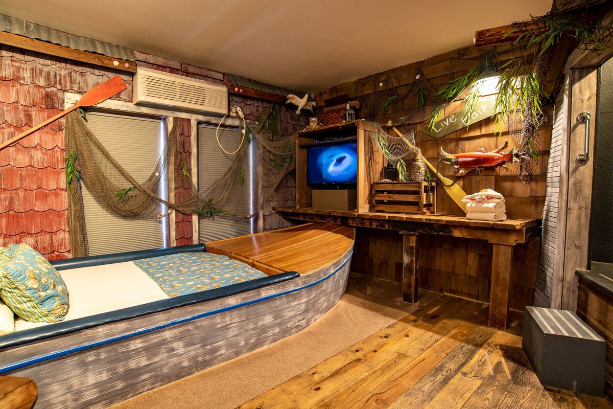 Un lit en forme de bateau, doté d’un téléviseur, de murs en bois et d’une décoration rustique.