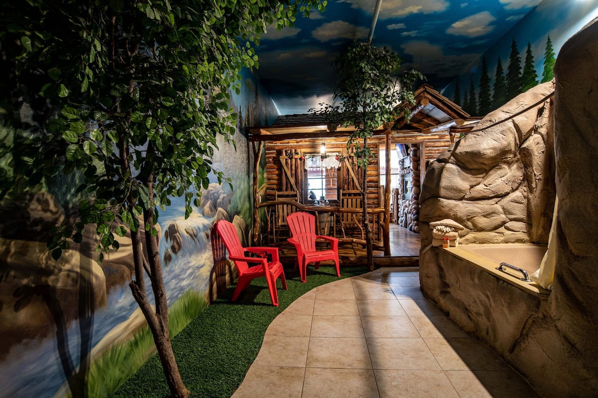 Une chambre de style rustique, aménagée comme un chalet, avec un mur en pierre, un banc en bois et un petit lavabo.