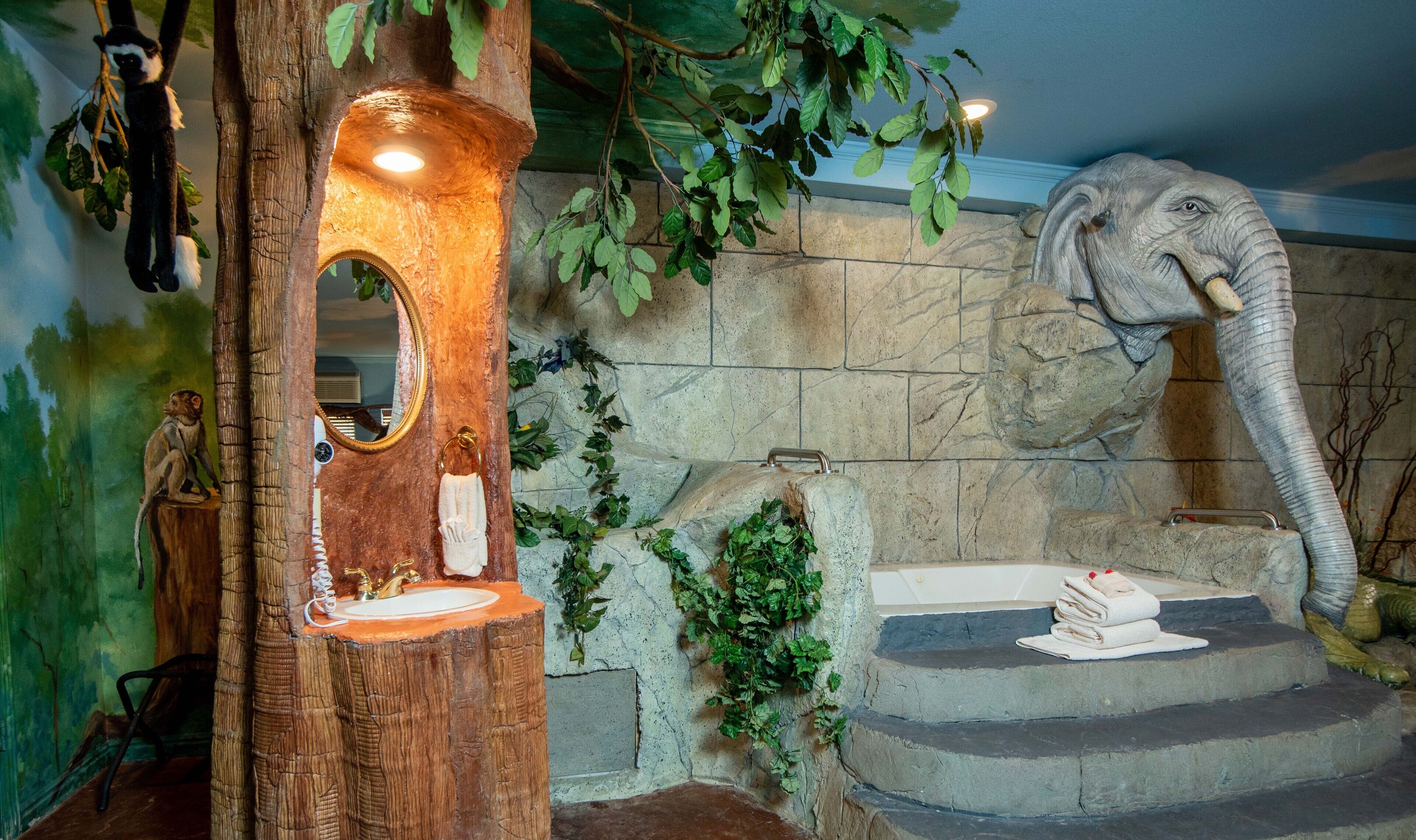 A room with a tree-shaped mirror, a stone wall, and a statue of an elephant.