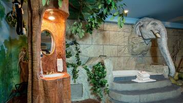 A room with a tree-shaped mirror, a stone wall, and a statue of an elephant.